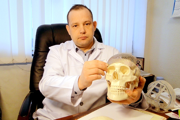 А. Сірко показує, як з допомогою титанової пластини буде відновлювати череп хворого